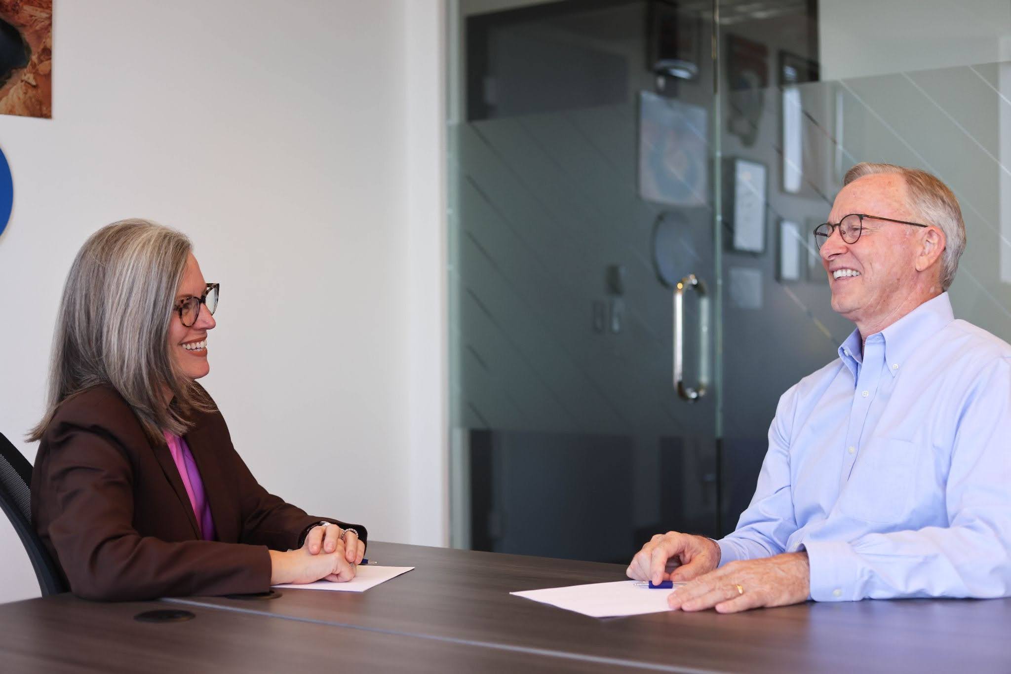 Katie Hobbs (left) and John Giles (right) sat at a table smiling at each other 